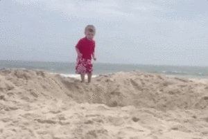kid jumping into hole in the sand